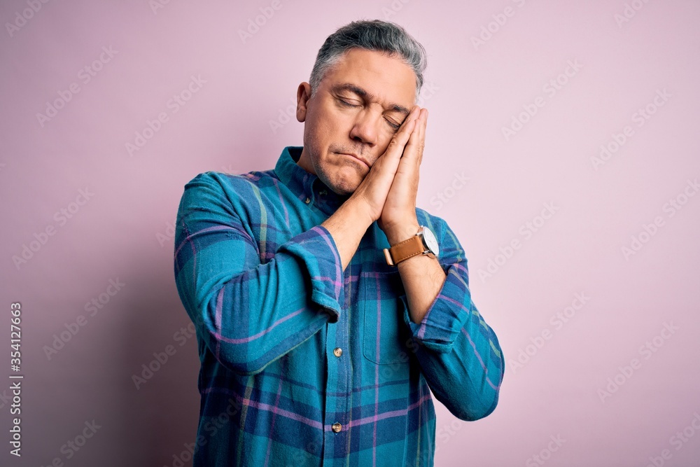Middle age handsome grey-haired man wearing casual shirt over isolated pink background sleeping tired dreaming and posing with hands together while smiling with closed eyes. Middle age handsome grey-haired man wearing casual shirt over isolated pink background sleeping tired dreaming and posing with hands together while smiling with closed eyes.