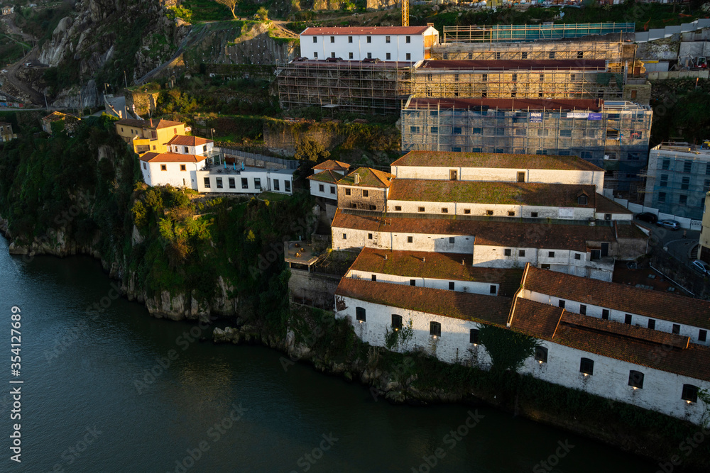 Port wine cellars in douro river bank. White buildings with orange roof lit by the warm sunset light. Porto, Portugal.