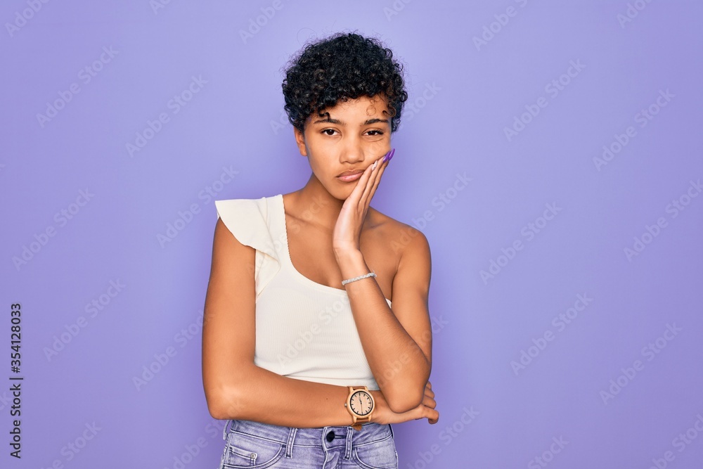 Young beautiful african american afro woman wearing casual t-shirt over purple background thinking looking tired and bored with depression problems with crossed arms. Young beautiful african american afro woman wearing casual t-shirt over purple background thinking looking tired and bored with depression problems with crossed arms.