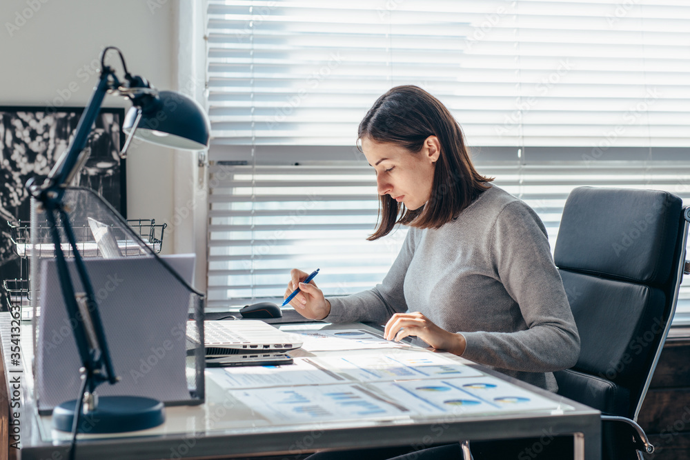 Woman working at her desk, taking notes Woman working at her desk, taking notes