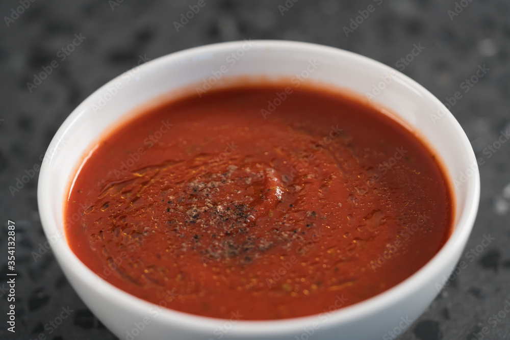 spicy tomato soup puree in white bowl on concrete background spicy tomato soup puree in white bowl on concrete background