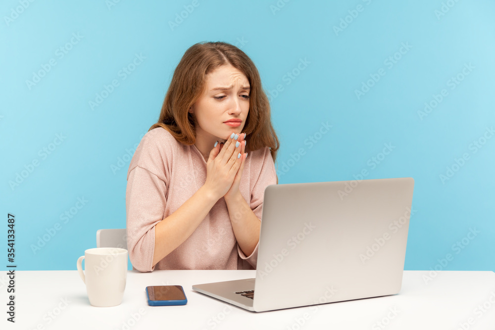 Please, begging for help! Young woman employee holding hands in praying gesture and talking on video call on laptop, asking heartily, pleading with desperate face. indoor studio shot, blue background Please, begging for help! Young woman employee holding hands in praying gesture and talking on video call on laptop, asking heartily, pleading with desperate face. indoor studio shot, blue background