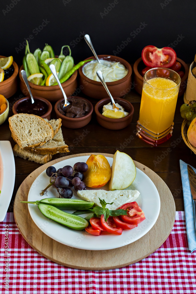 Meatless and Eggless Breakfast with fresh fruits,cheese,olives,dry fruits,fresh orange juice,whole wheat bread and fresh vegetables on the wooden table.