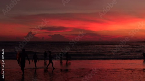 Wallpaper Mural Scenic view of beach in sunset with young surfer man going with surfboard and people walking along sea coast of Bali island during vacations  Torontodigital.ca