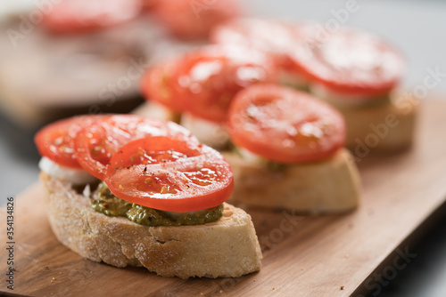 Bruschetta with tomatoes, mozzarella and pesto on olive wood board