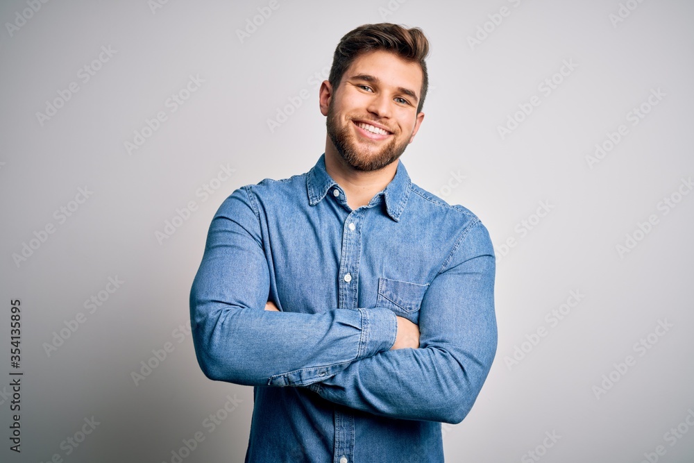 Young handsome blond man with beard and blue eyes wearing casual denim shirt happy face smiling with crossed arms looking at the camera. Positive person. Young handsome blond man with beard and blue eyes wearing casual denim shirt happy face smiling with crossed arms looking at the camera. Positive person.