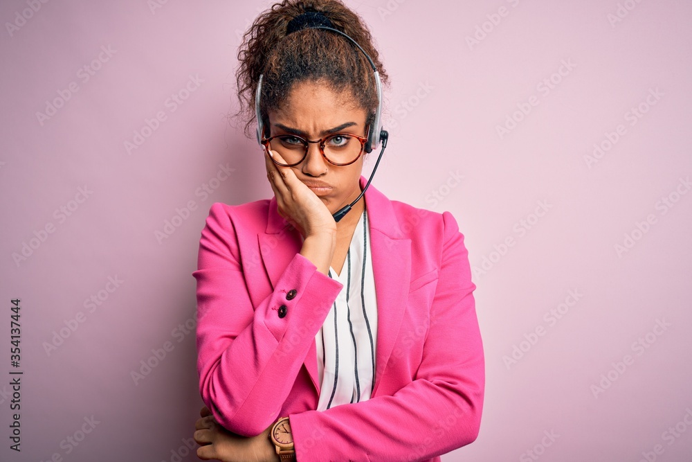 Young african american call center agent girl wearing glasses working using headset thinking looking tired and bored with depression problems with crossed arms.