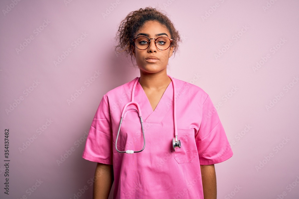 African american nurse girl wearing medical uniform and stethoscope over pink background Relaxed with serious expression on face. Simple and natural looking at the camera. African american nurse girl wearing medical uniform and stethoscope over pink background Relaxed with serious expression on face. Simple and natural looking at the camera.
