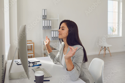 Side view. Business woman brunette meditates at the workplace at the table in the office.