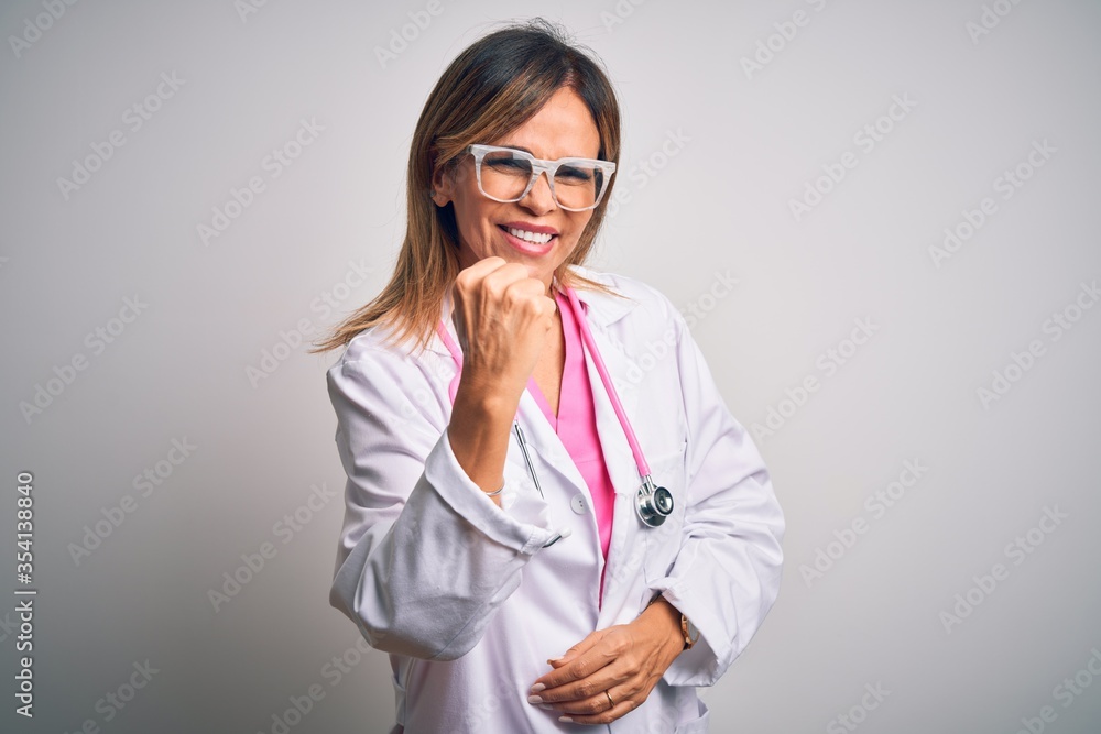Middle age beautiful doctor woman wearing pink stethoscope over isolated white background angry and mad raising fist frustrated and furious while shouting with anger. Rage and aggressive concept. Middle age beautiful doctor woman wearing pink stethoscope over isolated white background angry and mad raising fist frustrated and furious while shouting with anger. Rage and aggressive concept.