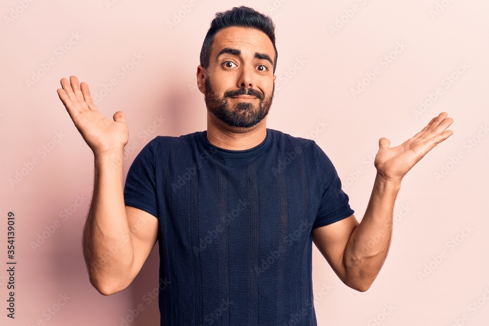 Naklejka premium Young hispanic man wearing casual clothes clueless and confused with open arms, no idea and doubtful face.