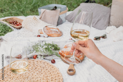 Aesthetic picnic outdoors with wine glasses bread berries and flowers. Rustic picnic with neutral tones colours. 