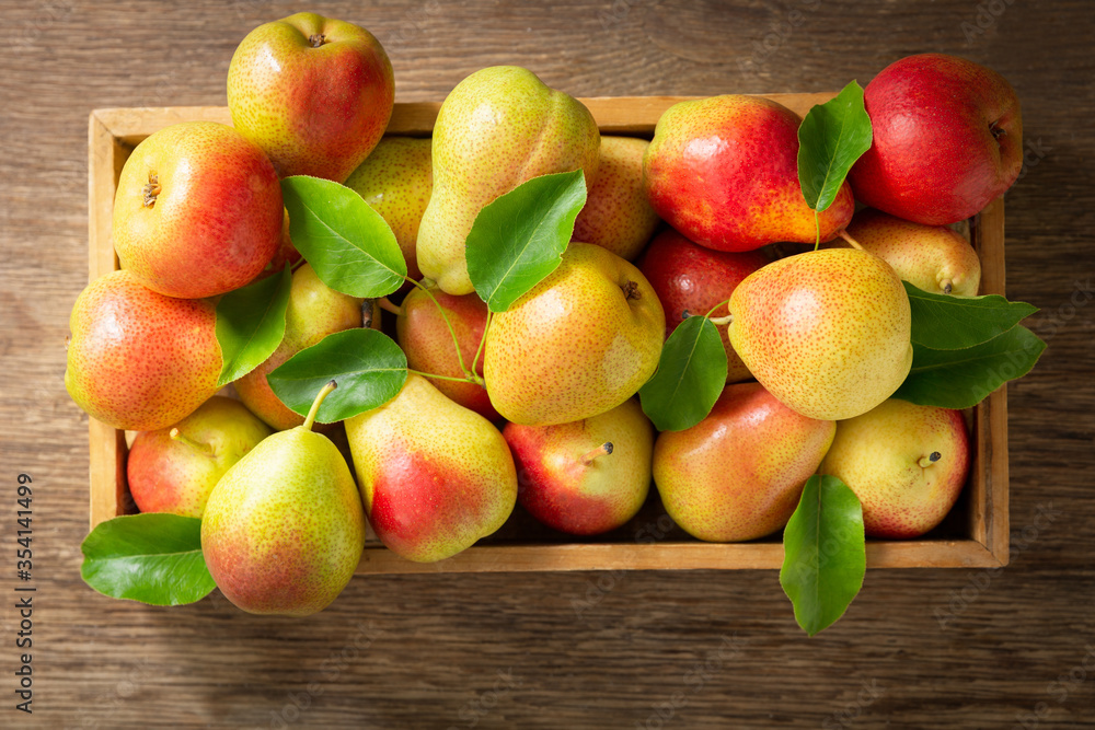 fresh pears with leaves in a box on a wooden table, top view fresh pears with leaves in a box on a wooden table, top view