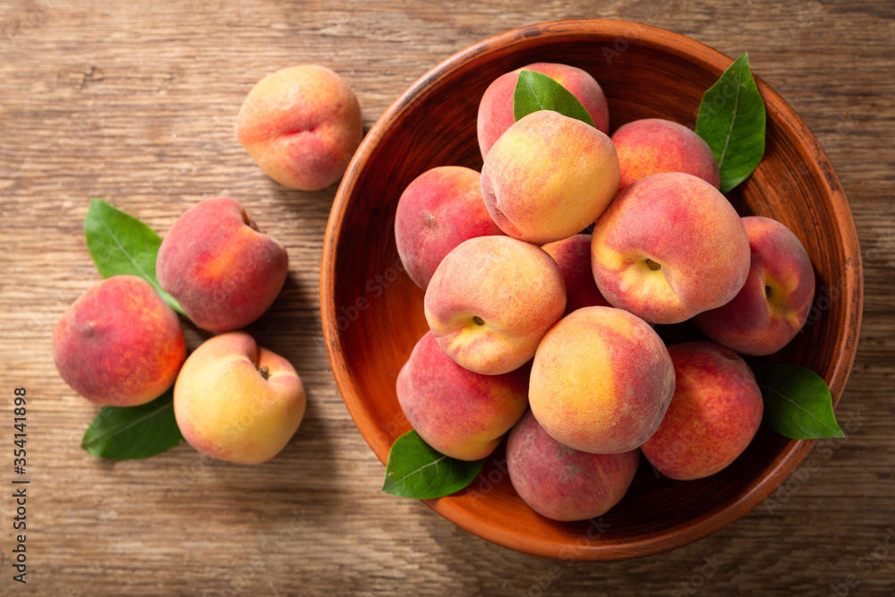 fresh ripe peaches with leaves in a bowl, top view fresh ripe peaches with leaves in a bowl, top view