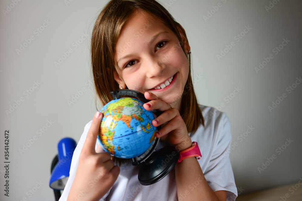 Portrait of a beautiful young schoolgirl girl exploring the globe through a magnifier. day of knowledge. beginning of the school year. studying geography with globe Portrait of a beautiful young schoolgirl girl exploring the globe through a magnifier. day of knowledge. beginning of the school year. studying geography with globe