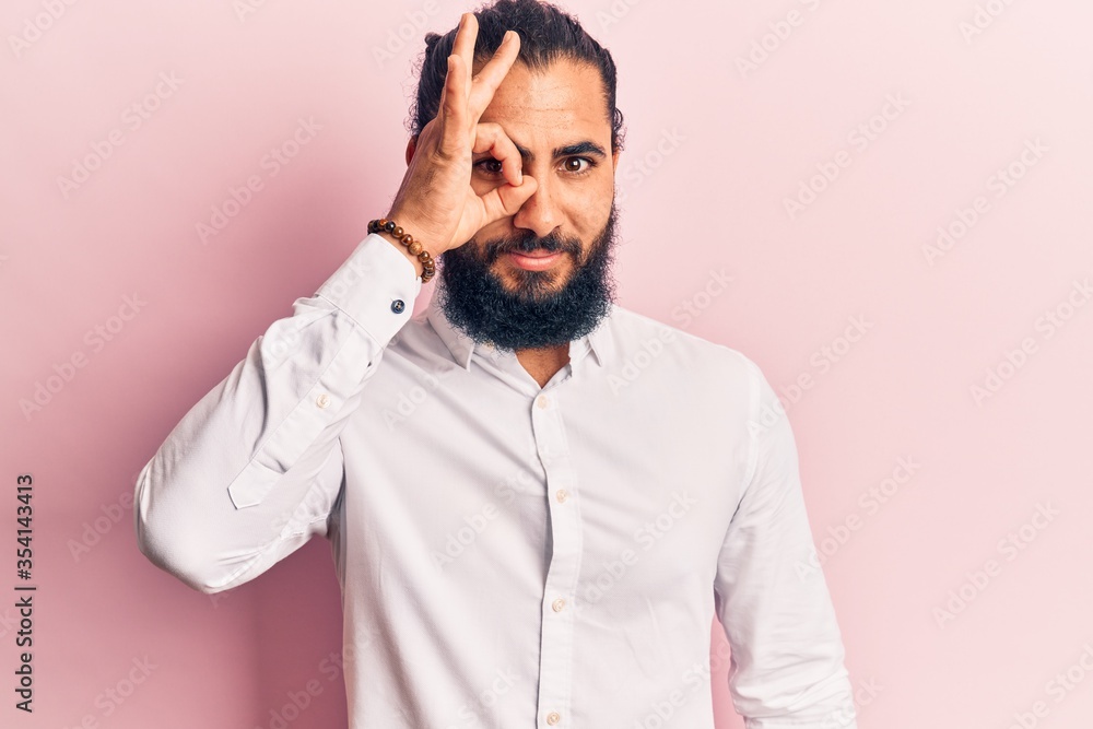 Fototapeta premium Young arab man wearing casual clothes doing ok gesture with hand smiling, eye looking through fingers with happy face.
