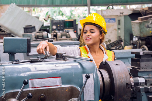 Happy smile female mechanical engineer or employee worker with yellow safety helmet in a factory.  Happy Work.