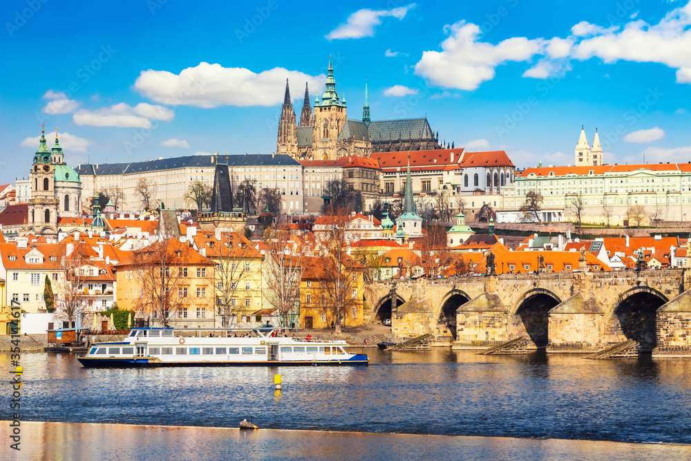 Prague Castle, Charles bridge, Mala Strana district and sightseeing touristic ship during summer sunny day in Prague, Czech Republic.