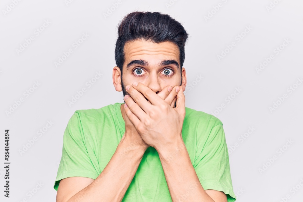 Young handsome man with beard wearing casual t-shirt shocked covering mouth with hands for mistake. secret concept. Young handsome man with beard wearing casual t-shirt shocked covering mouth with hands for mistake. secret concept.