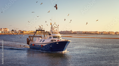Fishing boat at sunset arriving at the port of Isla Cristina, after a long day at work in the waters of the Atlantic Ocean, Spain