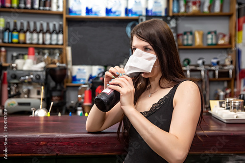 girls in medical masks drink cocktails. girl in a medical mask is resting in a pub. girl in a medical mask in a pub