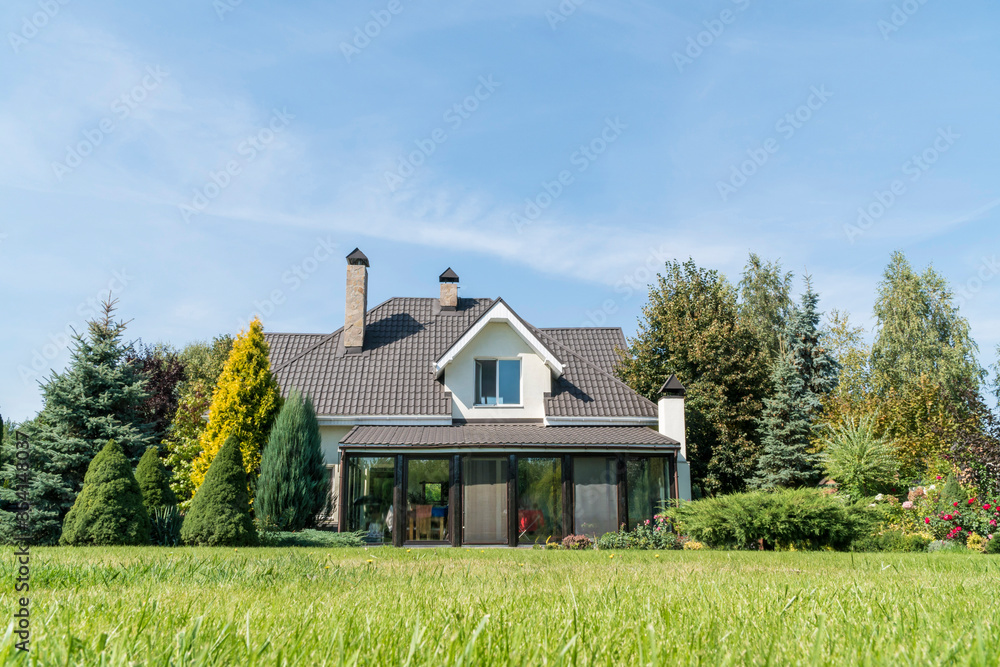 private house with its beautiful garden in a rural area under blue sky