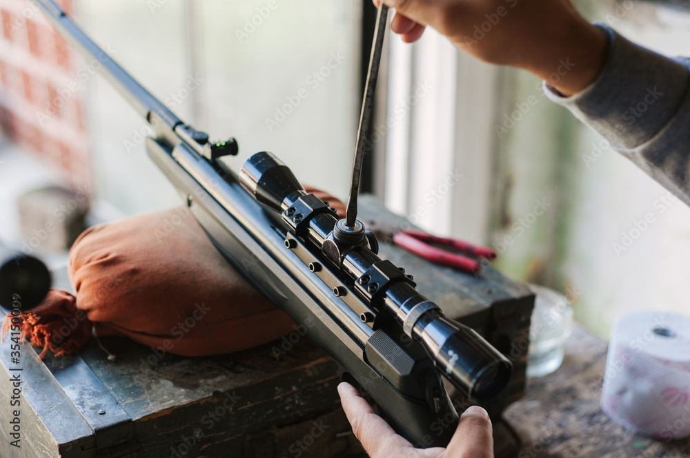 The gunsmith adjusts the optical sight of the sport air rifle ...
