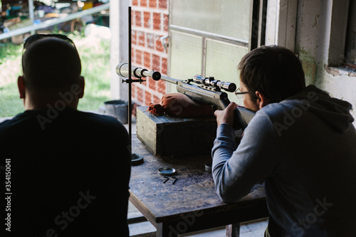 The gunsmith adjusts the optical sight of the sport air rifle. Adjusting the sniper rifle at a distance