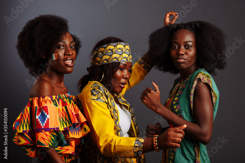Three young beautiful African fashion models have fun and laughing in traditional dress. Women from the Congo Republic, Ivory Coast, and Zimbabwe