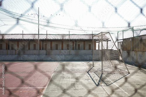 Abandoned football field and soccer goal, view through a net, ideal for nostalgic and vintage. Urban location