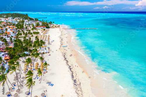 Aerial drone view of beautiful atlantic tropical beach with palms, straw umbrellas and boats. Bavaro, Punta Cana, Dominican Republic. Vacation background.