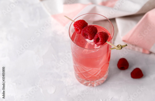 Pink rose iced cocktail with raspberry in crystal glass on table photo