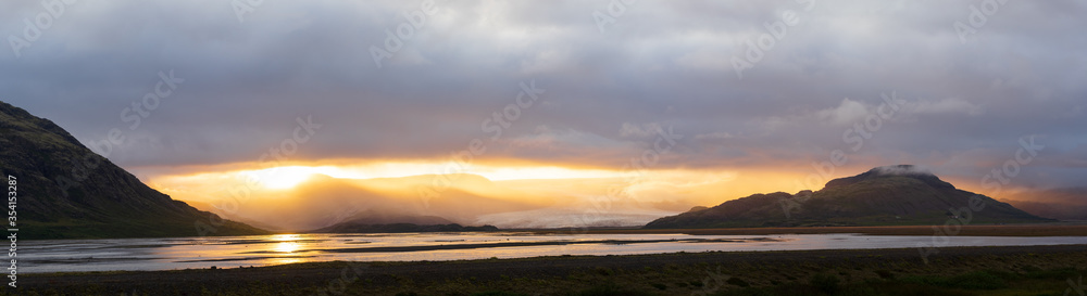 Sun breaking through clouds between mountains, mystical sunset in Iceland