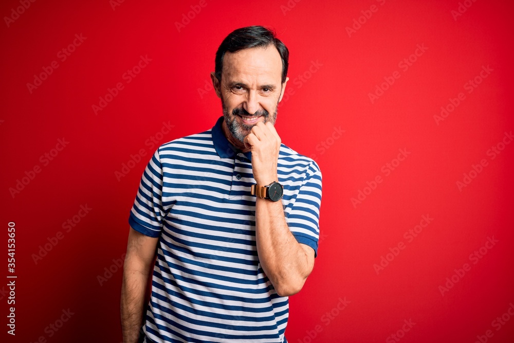 Middle age hoary man wearing casual striped polo standing over isolated red background looking confident at the camera with smile with crossed arms and hand raised on chin. Thinking positive. Middle age hoary man wearing casual striped polo standing over isolated red background looking confident at the camera with smile with crossed arms and hand raised on chin. Thinking positive.