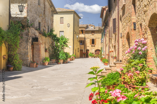 Fototapeta Naklejka Na Ścianę i Meble -  Sunny streets with colorful flowers with contrasting shades. Walk the Tuscan town