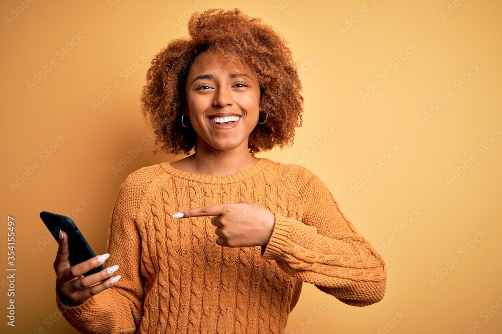 Young African American afro woman with curly hair having conversation using smartphone very happy pointing with hand and finger Young African American afro woman with curly hair having conversation using smartphone very happy pointing with hand and finger