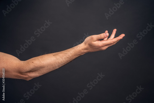 Man hand isolated on grey background. Holding something from below. Asking for help gesture.