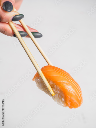 Sushi with salmon in wooden chopsticks. White background