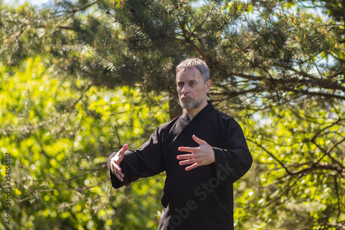a male tai Chi master practices qigong in nature in a Park