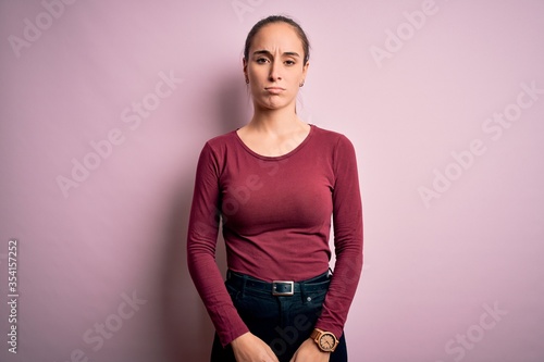 Young beautiful woman wearing casual t-shirt standing over isolated pink background depressed and worry for distress, crying angry and afraid. Sad expression.