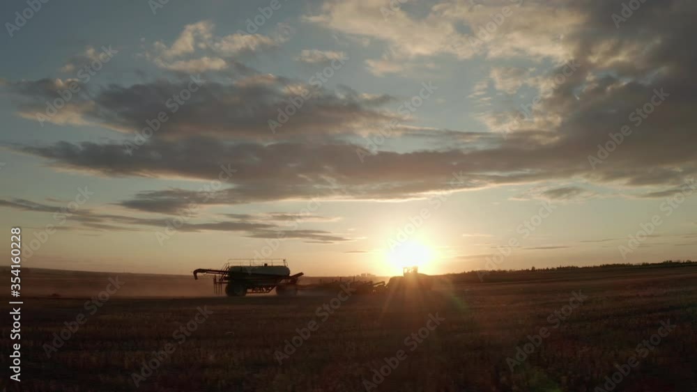 A Tractor Seeder At Work In The Farm During Sunrise In Swift Current, Saskatchewan, Canada - wide drone shot A Tractor Seeder At Work In The Farm During Sunrise In Swift Current, Saskatchewan, Canada - wide drone shot