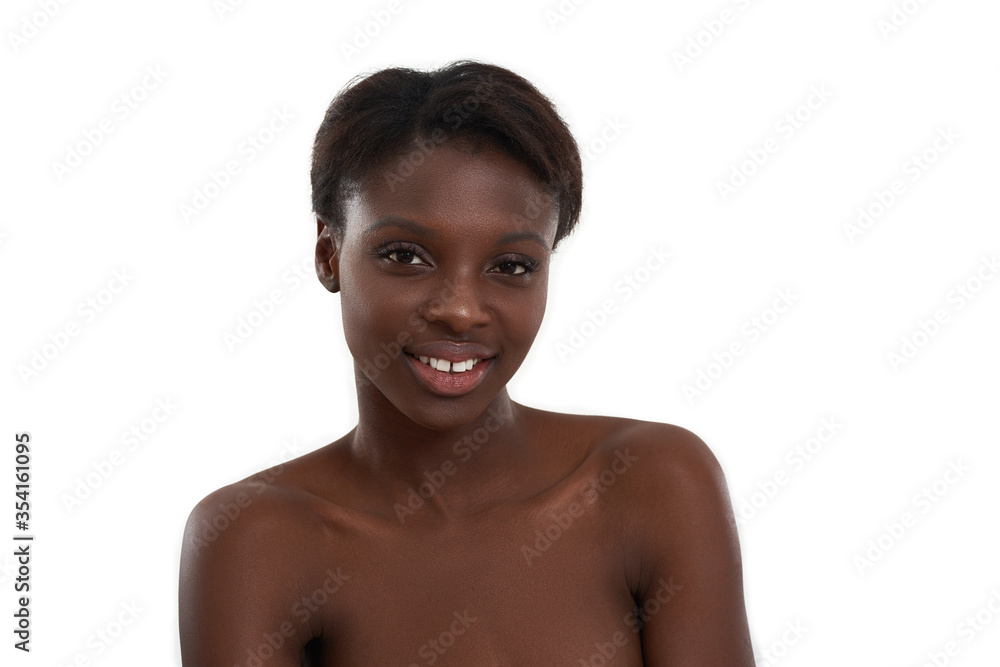 Pure beauty. Portrait of a young and cheerful african woman looking at camera and smiling while standing against white background