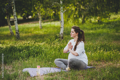 Healthy pregnant woman doing yoga in nature outdoors. © marina_li_1