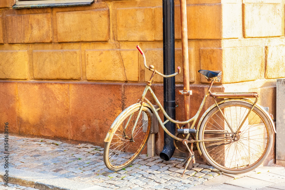 Old bicycle near yellow medieval house of Gamla Stan historic old center of Stockholm at summer sunny day.