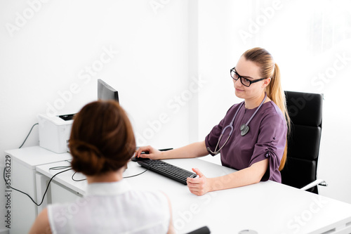 Close up of female doctor and patient sitting at the desk in modern clinic. photo