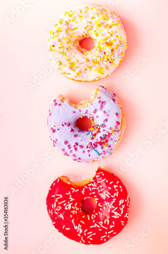Colored donuts with colorful sprinkles on pink background. National Donut or Doughnut day concept