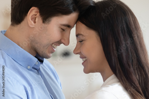 Close up of happy young caucasian couple look in eyes touch forehead enjoy tender romantic intimate moment together, smiling millennial man and woman lovers show affection and love in relationships