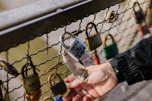 Hand holding a padlock in the Kladka Ojca Bernatka bridge in Poland, Krakow