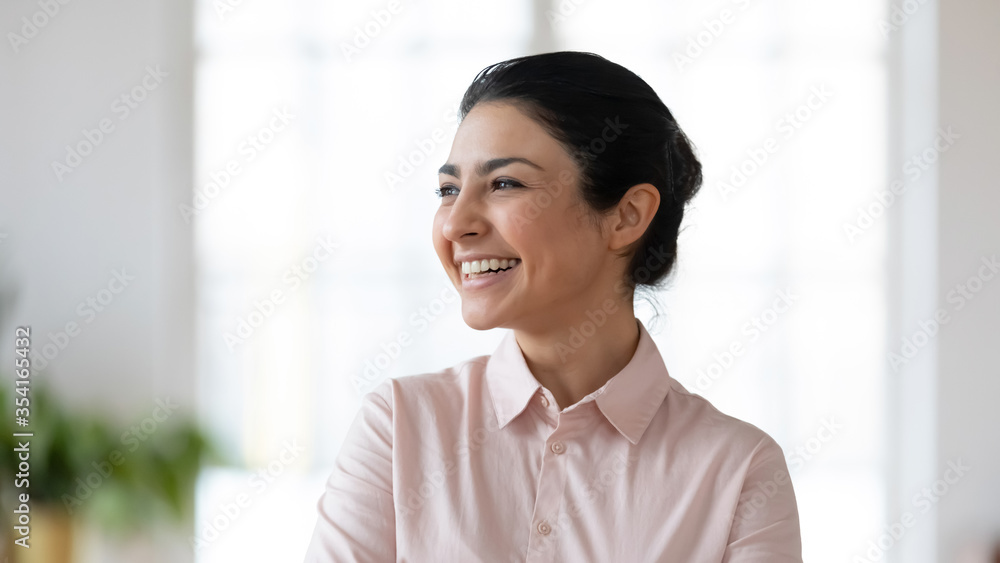 Close up head shot laughing young indian businesswoman looking away. Happy smiling millennial hindu ethnicity employee planning future job, thinking of new challenges opportunities in office. Close up head shot laughing young indian businesswoman looking away. Happy smiling millennial hindu ethnicity employee planning future job, thinking of new challenges opportunities in office.