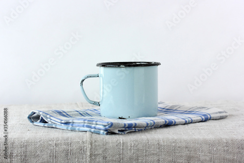 Foto blue enamel mug on a table with a linen tablecloth.